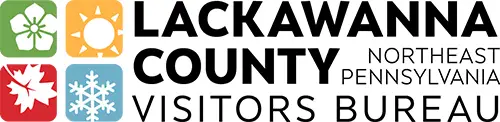 This is the logo for the Lackawanna County Visitors Bureau in Northeast Pennsylvania. The design includes four seasonal icons: a green flower, an orange sun, a red autumn leaf, and a blue snowflake. To the right, bold black text reads “Lackawanna County Visitors Bureau” with “Northeast Pennsylvania” in smaller lettering.